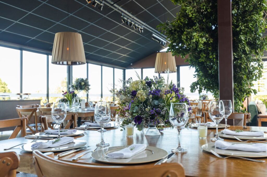 A beautifully set wedding reception table with floral centerpieces and glassware in a modern venue.